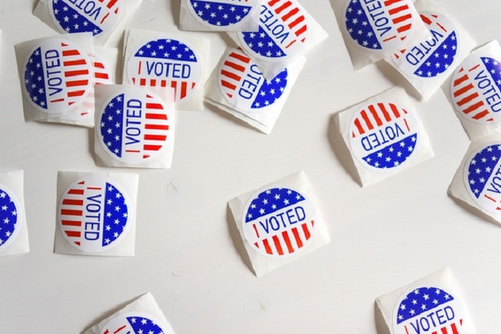 Scattered I Voted stickers with flag design on white background