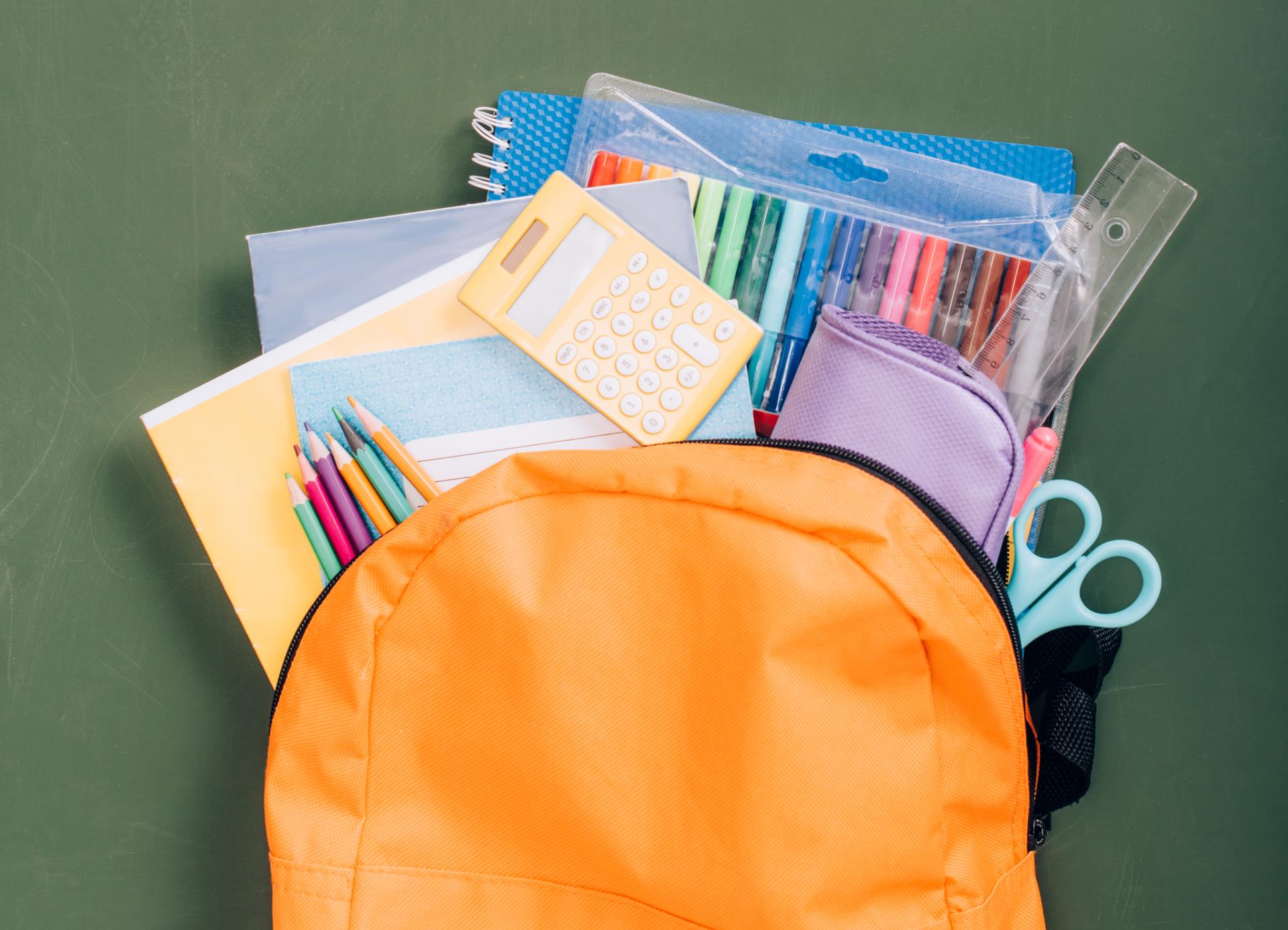 An image of an orange backpack with school supplies sticking out of the top