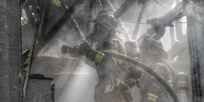 Firefighter carrying a hose into a burning building