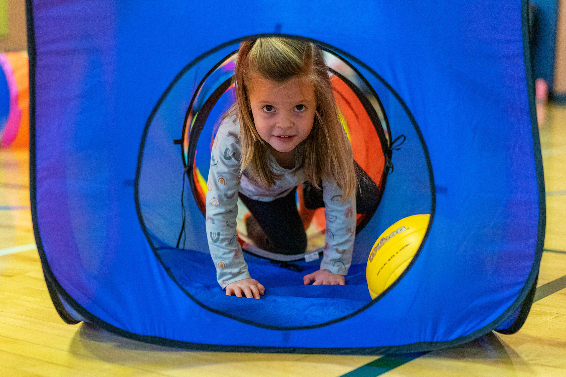 A girl crawls through a play tunnel