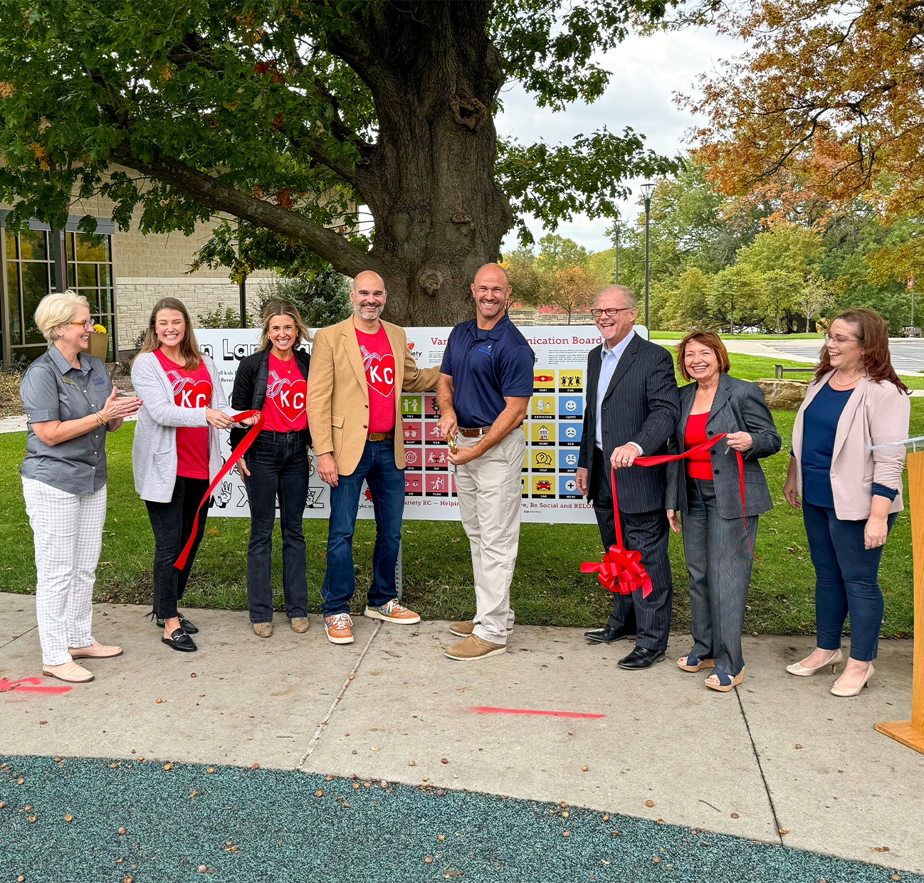 City council members, Variety KC staff and City employees pose for a photo in front of Adaptive Signage at a ribbon cutting ceremony