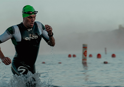 A man in a black wetsuit and green swimmer