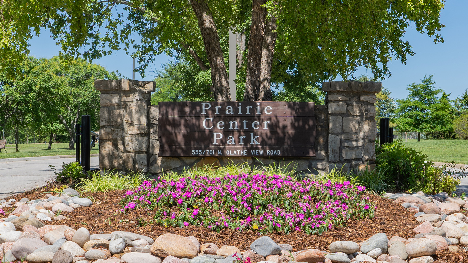 A wooden sign that reads "Prairie Center Park, 555/701 N. Olathe View Road"