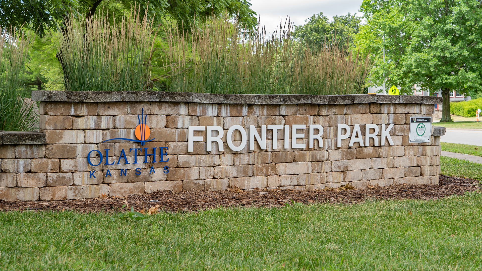 Brown brick wall with Olathe, Kansas logo and "Frontier Park" displayed on the front