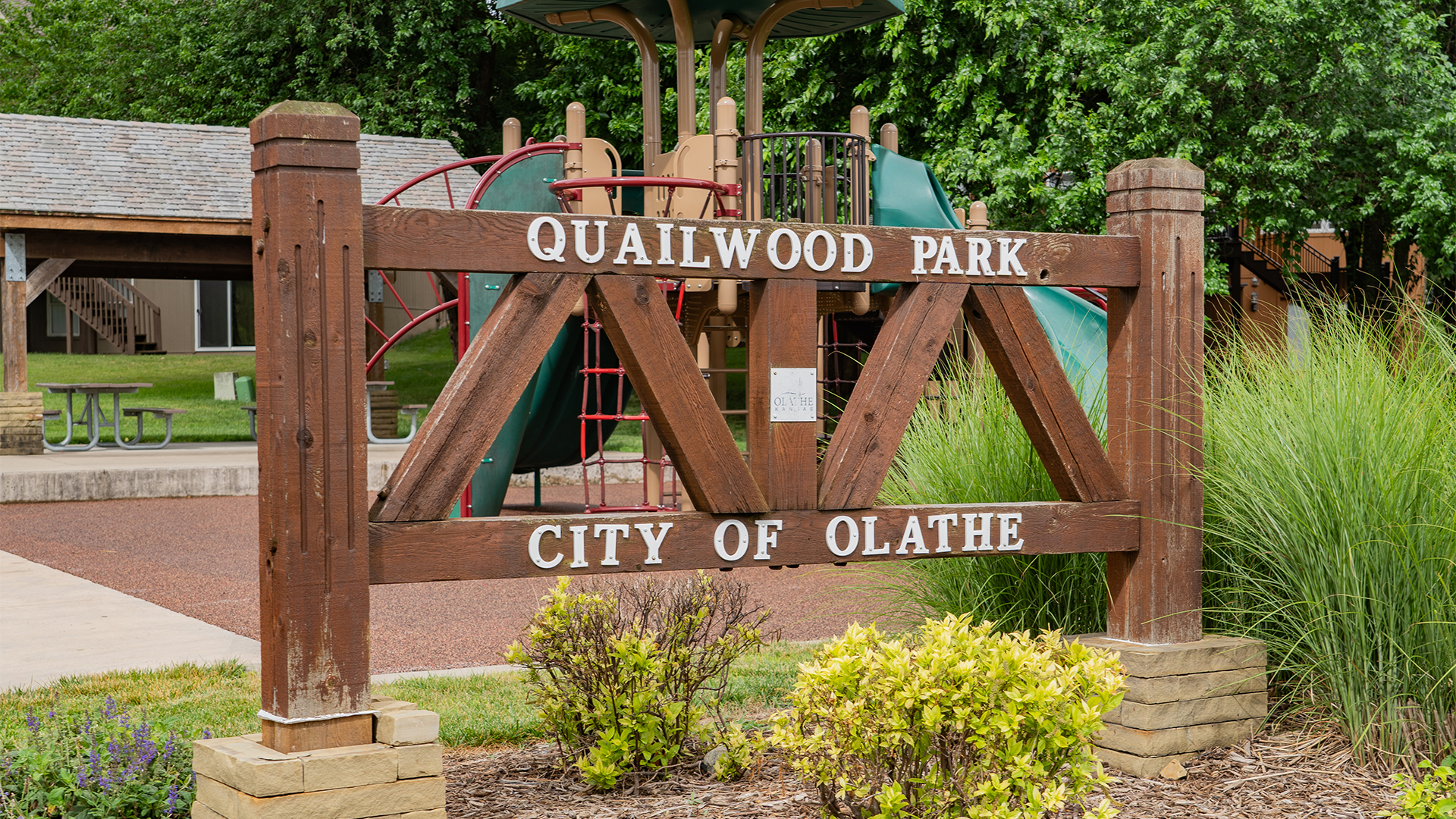 Wooden sign that reads "Quailwood Park" and "City of Olathe"