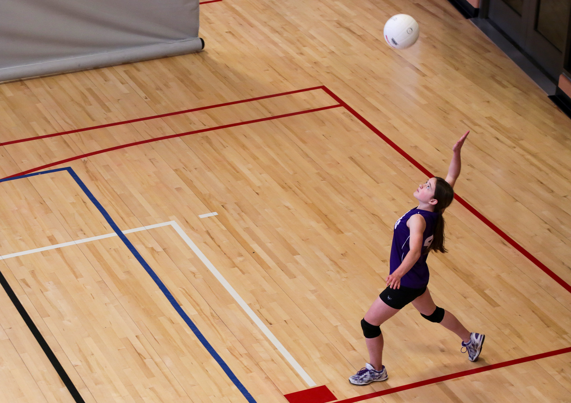 A girl attempts a serve in volleyball