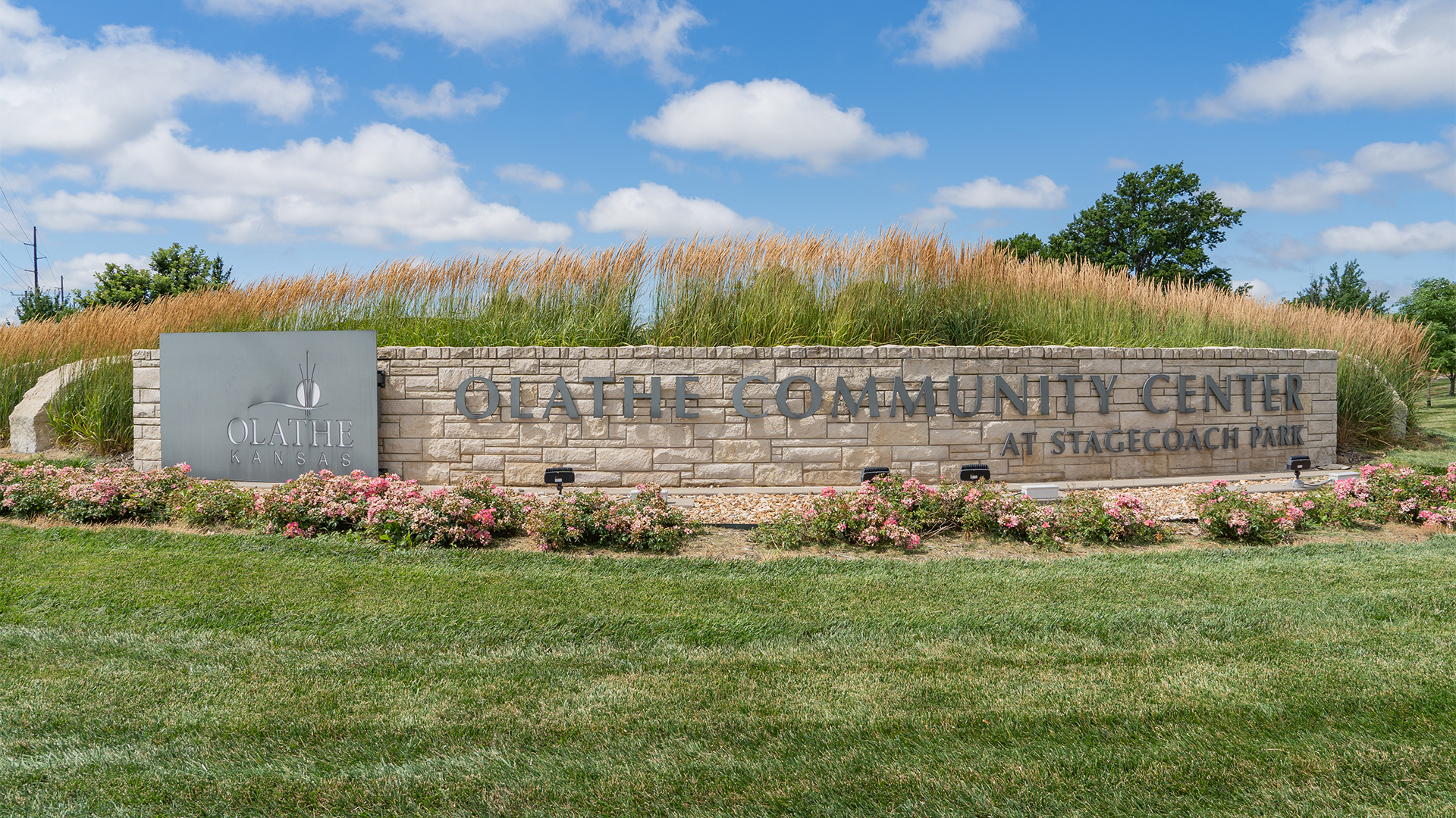 Tan brick sign with Olathe, Kansas logo that reads "Olathe Community Center at Stagecoach Park"