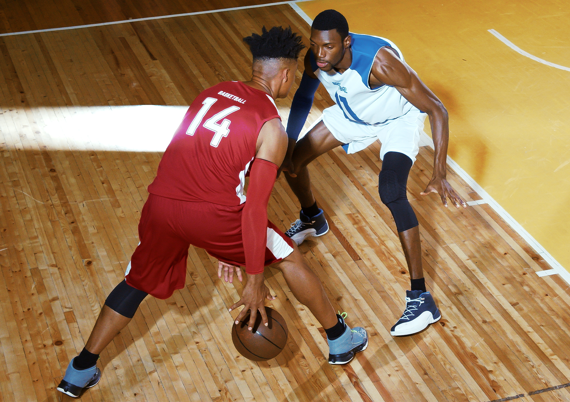 Two adult men playing basketball