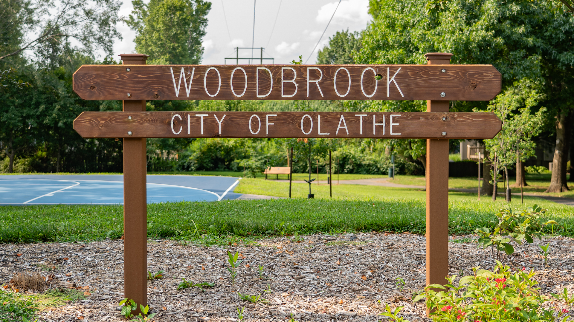 Wooden sign that states "Woodbrook" and "City of Olathe"