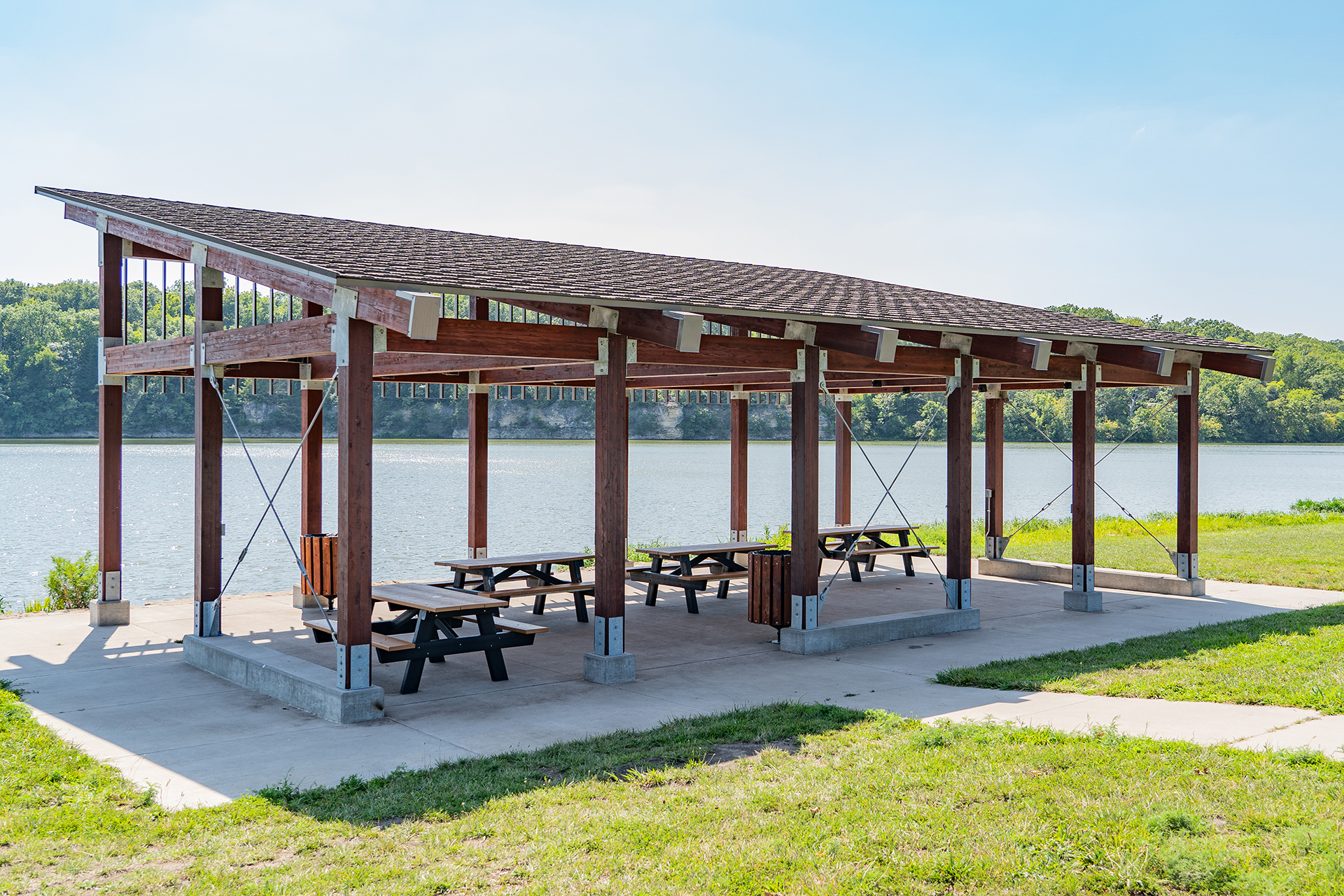 Wooden park shelter with picnic tables and trash cans overlooking the lake