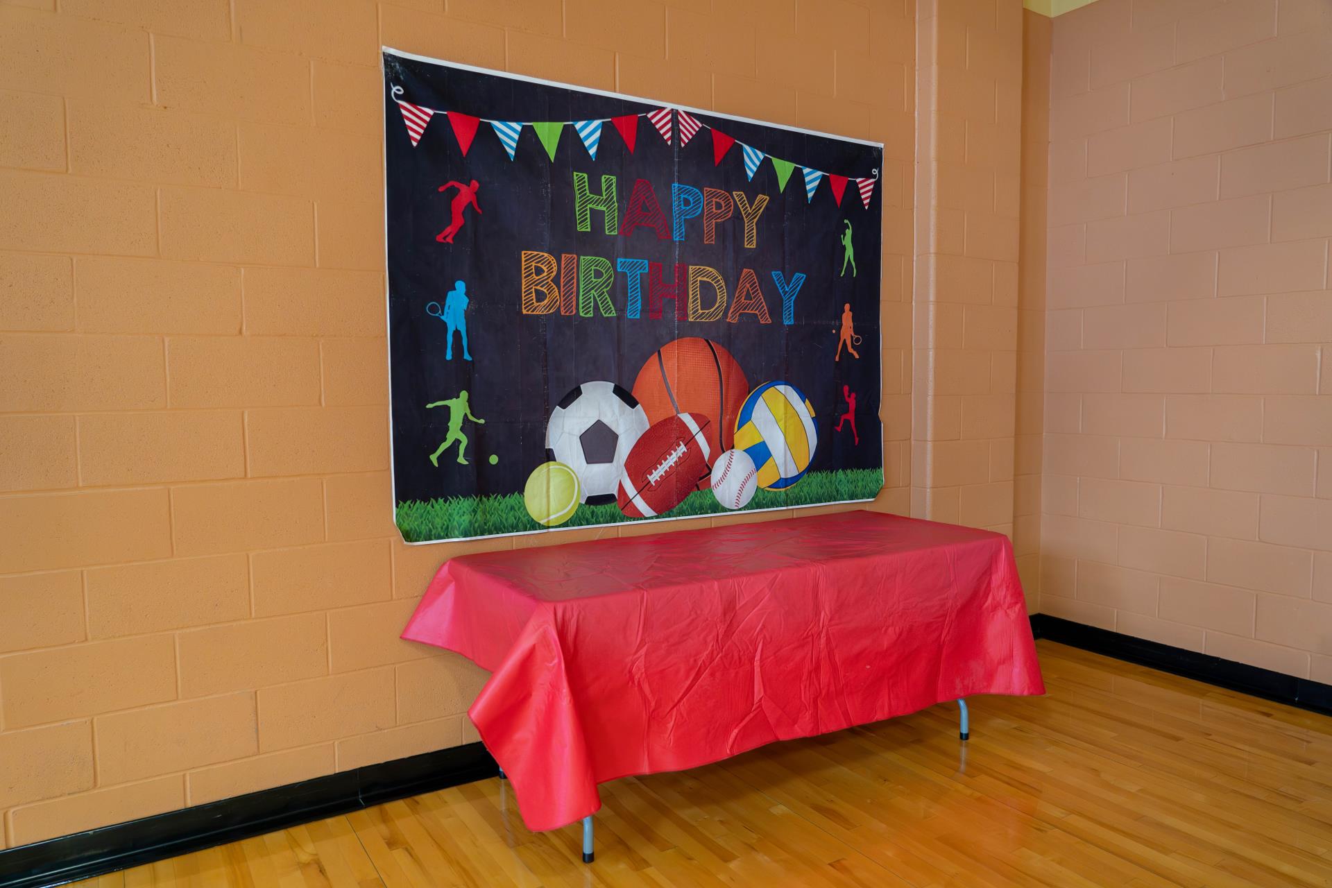 folding table with red drop cloth and happy birthday on wall